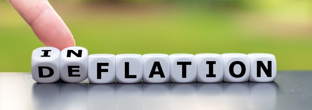 Hand turns a dice and changes the word "deflation" to "inflation